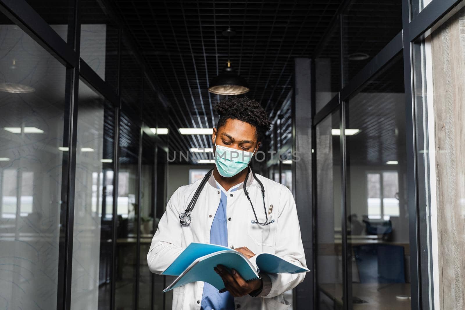 African doctor in mask with books in medical clinic. Black medical student study in university