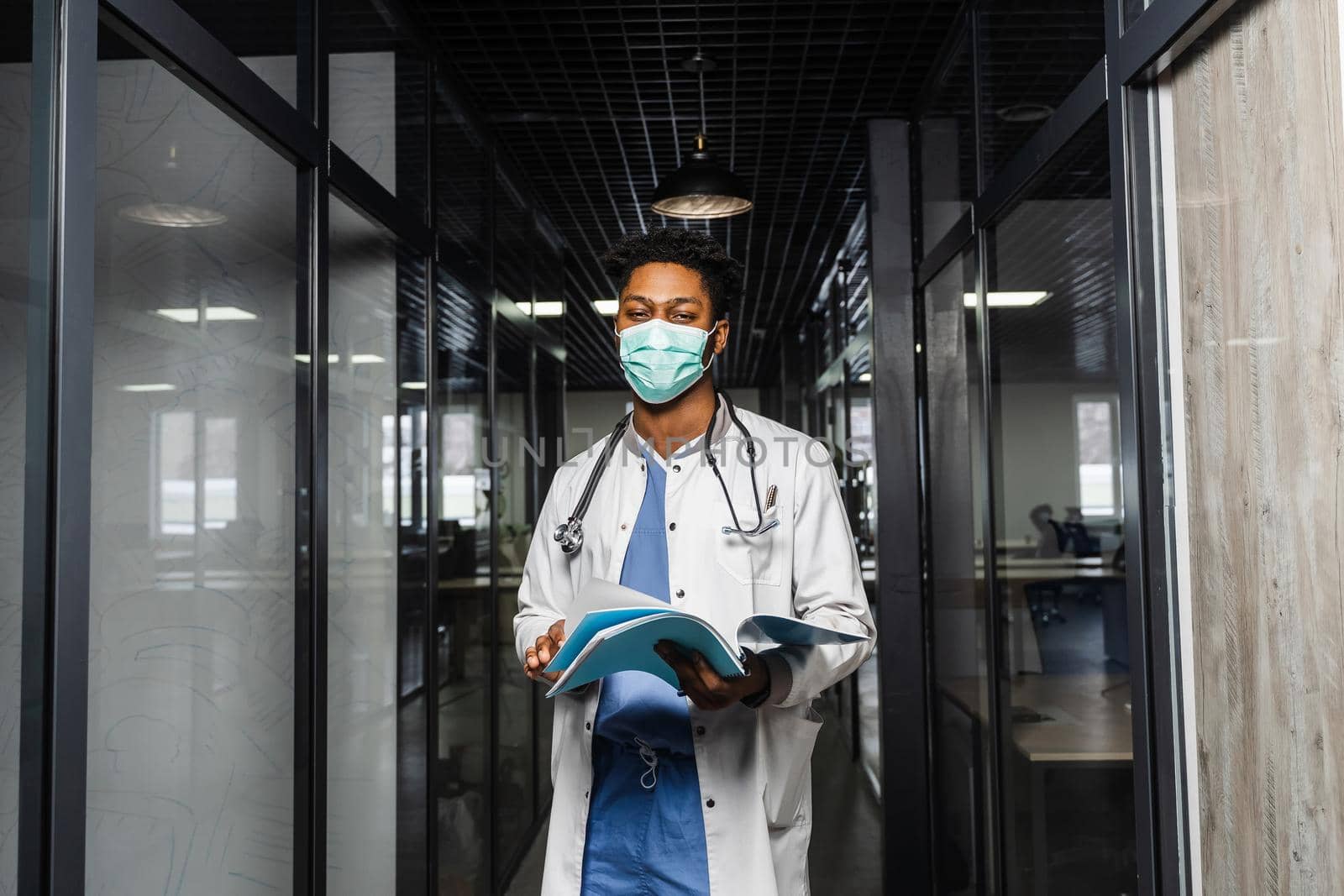 African doctor in mask with books in medical clinic. Black medical student study in university