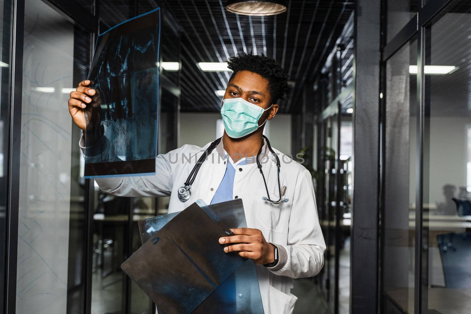 African doctor examines x-rays in a medical clinic. Black student in medical mask is studying and looking at ct scans. by Rabizo