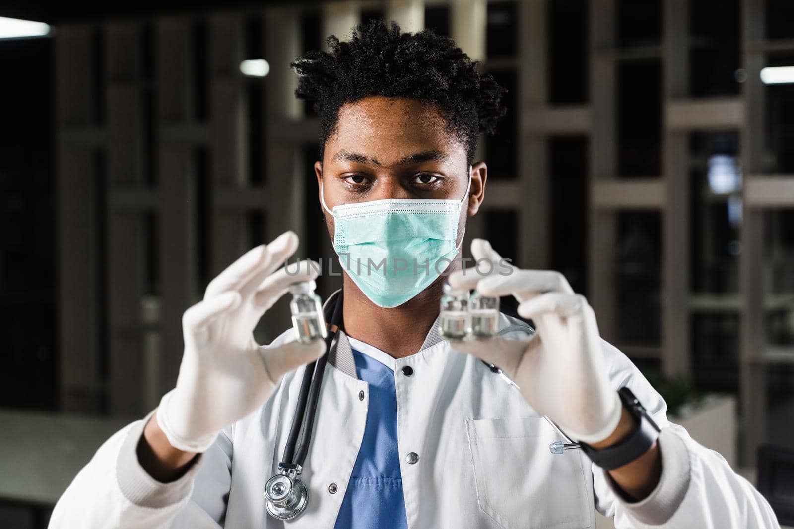 Black doctor with 3 doses of vaccine. Booster vaccination. African doctor in medical mask is holding vaccines in hand. by Rabizo