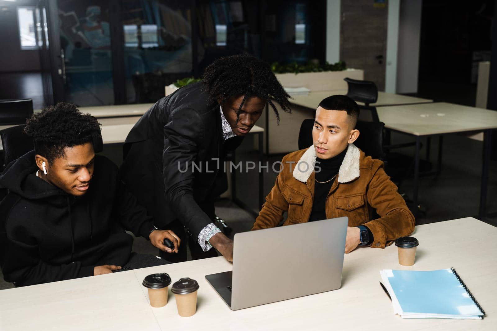 Teamwork of 2 black african and asian with laptop. Colleagues in informal clothes working on business project in the office
