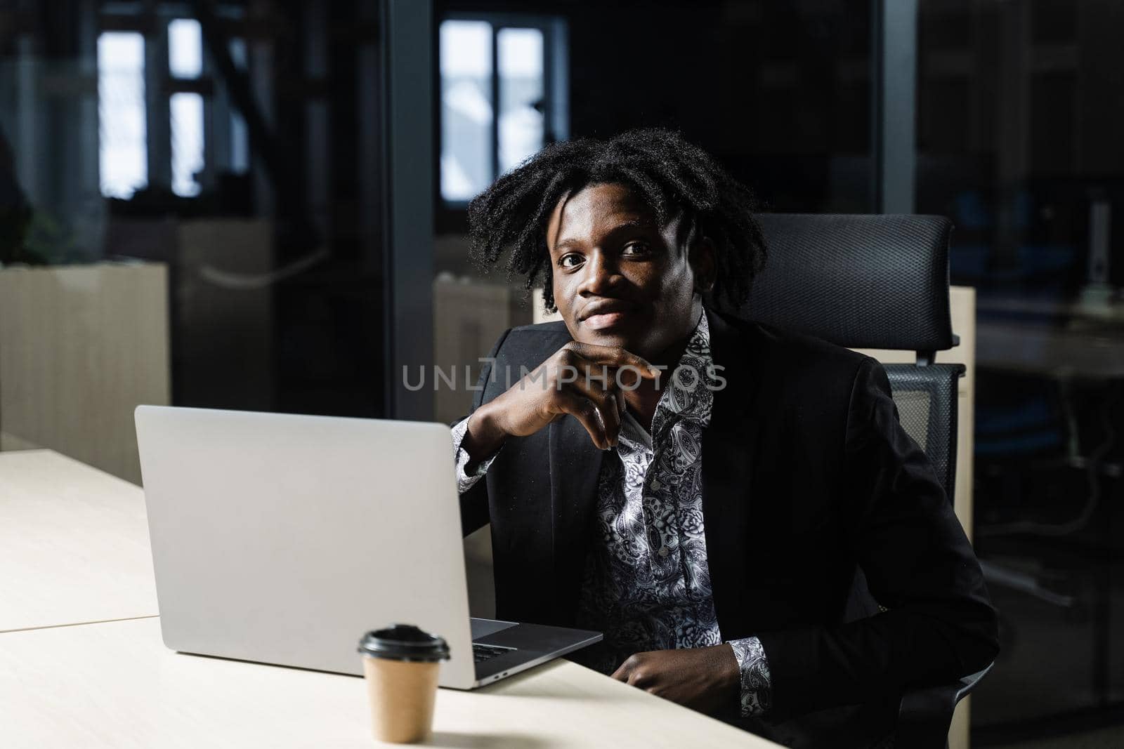 Black business man with laptop is working online in the office. Handsome african manager is doing remote work in coworking space. by Rabizo