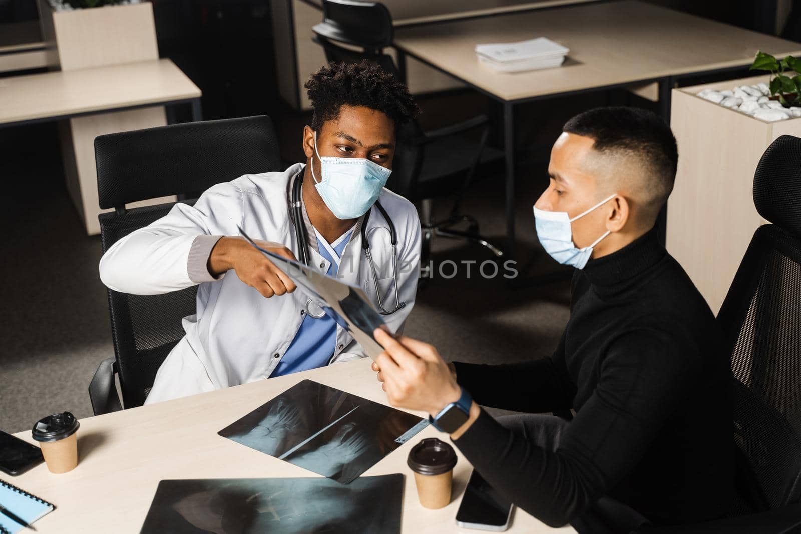 African doctor show x-ray asian patient. Pneumonia and pleurisy. Black surgeon analyzing x ray and diagnosis patient in medical clinic