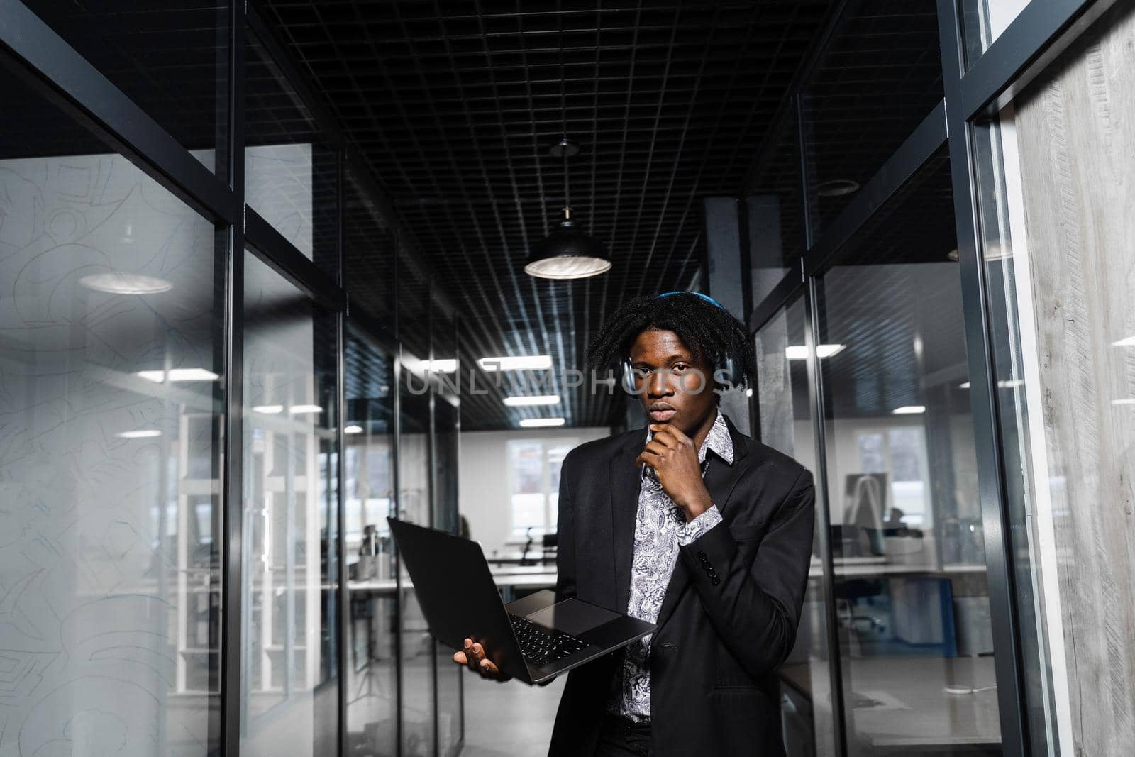 Confident black business man with laptop working online with his colleagues. Handsome african manager in the office. by Rabizo