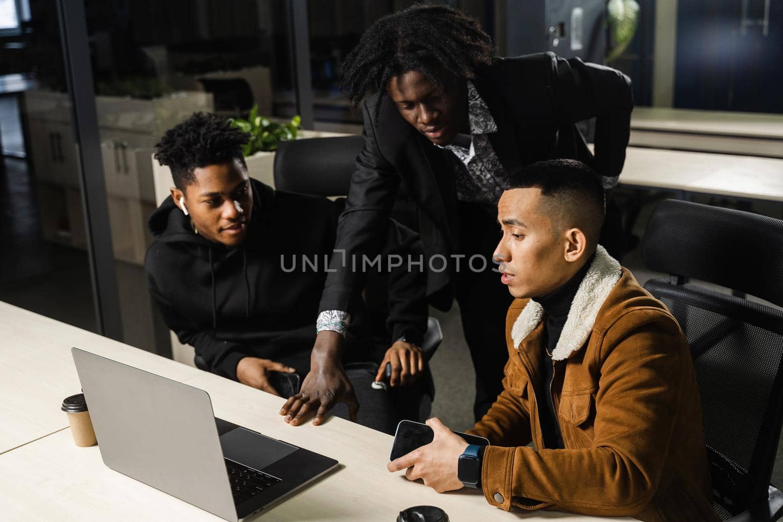 Mixed race of men teamwork on laptop in office. Discussing and working on on online projects