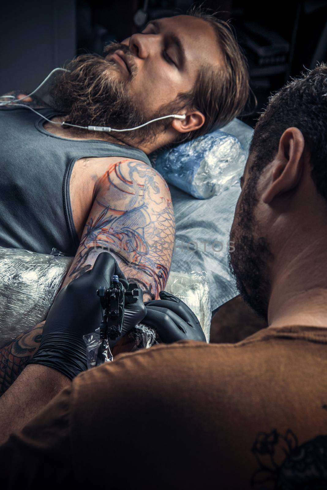 Professional tattoo artist showing process of making a tattoo in tattoo parlor by Proff
