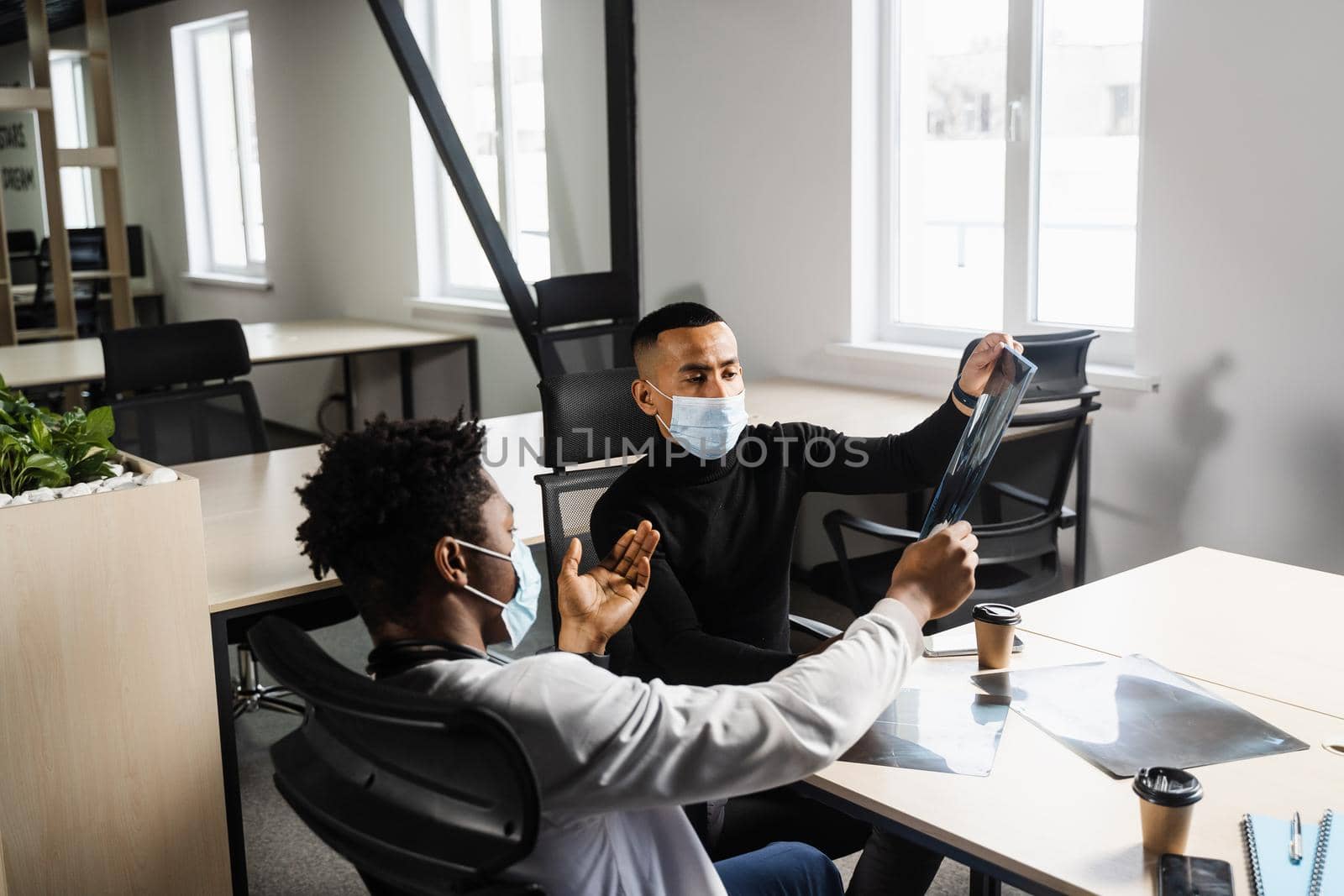 African doctor show x-ray asian patient. Black surgeon analyzing x ray and diagnosis patient in medical clinic