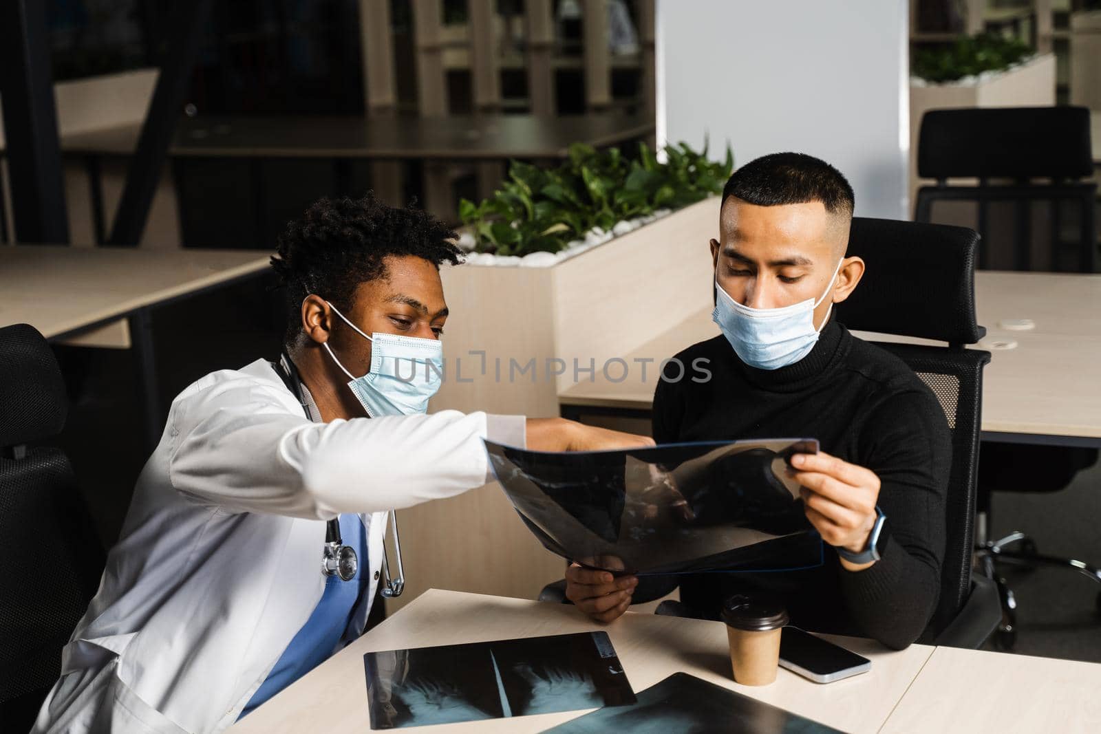 African doctor show x-ray asian patient. Black surgeon analyzing x ray and diagnosis patient in medical clinic