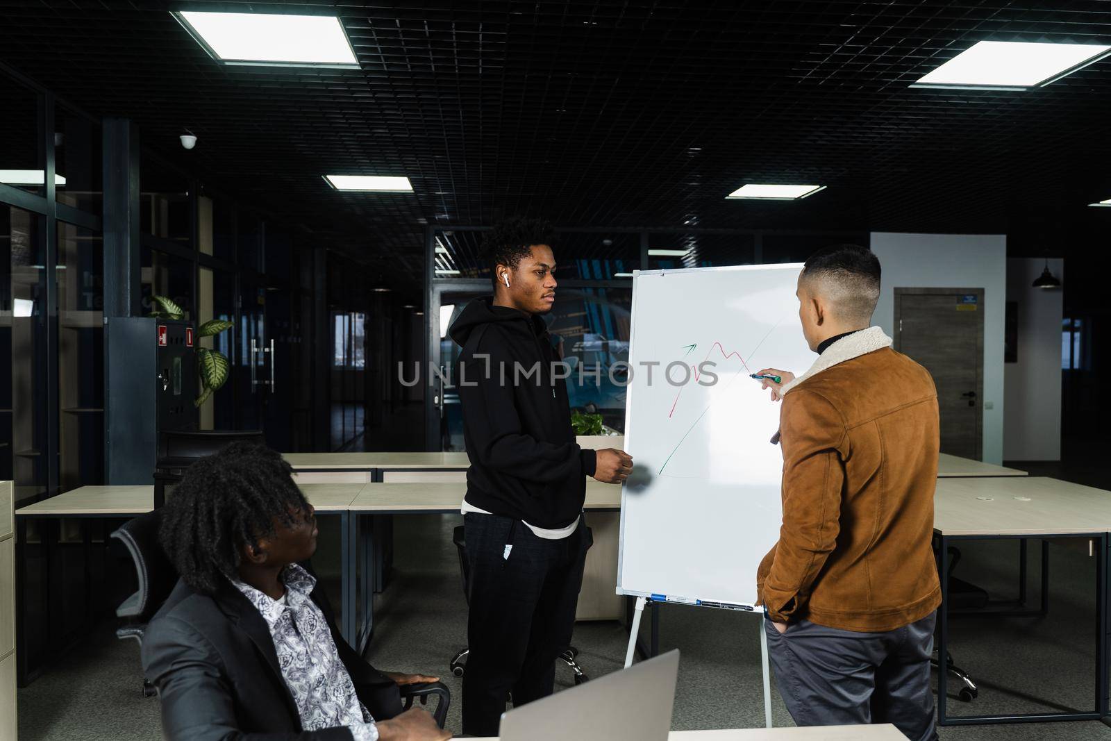 Cryptocurrencies and bitcoin graph discussion by multiethnic investors. Black African and Asian businessmen are discussing the economic financial situation together