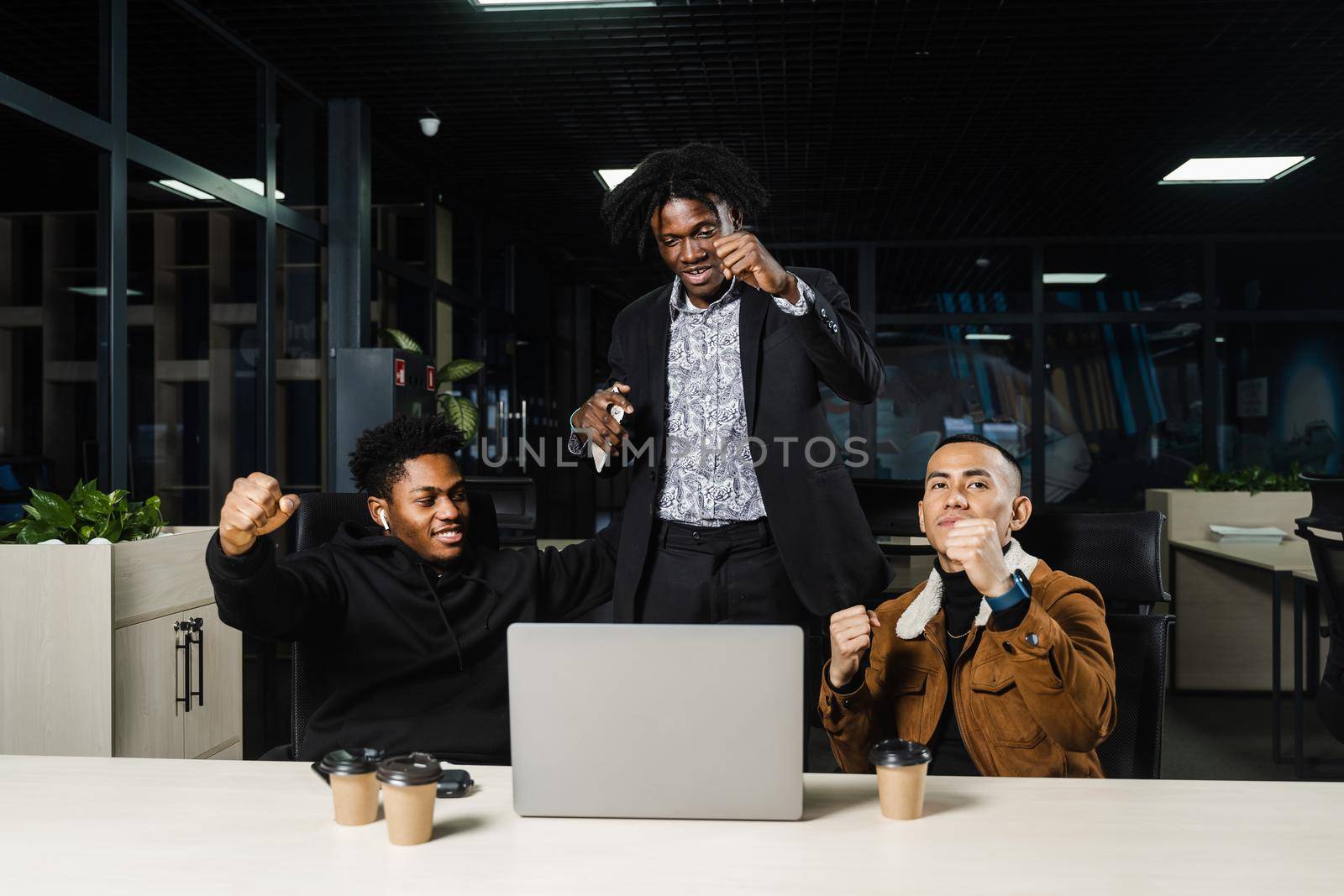 Teambuilding black Africans and Asians. Positive mixed race colleagues smile, rejoice in teamwork success on a joint project