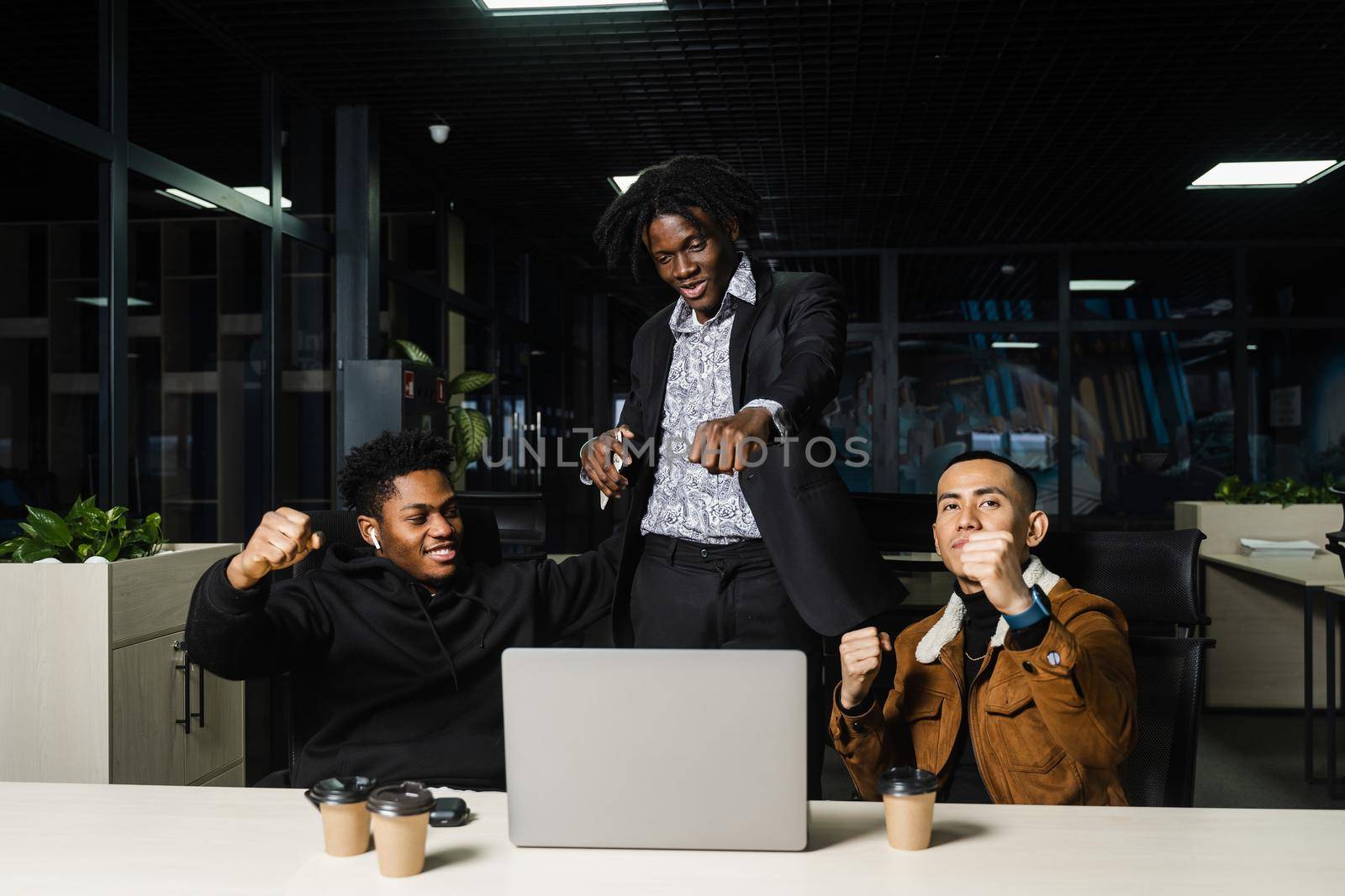 Teambuilding black Africans and Asians. Positive mixed race colleagues smile, rejoice in teamwork success on a joint project. by Rabizo