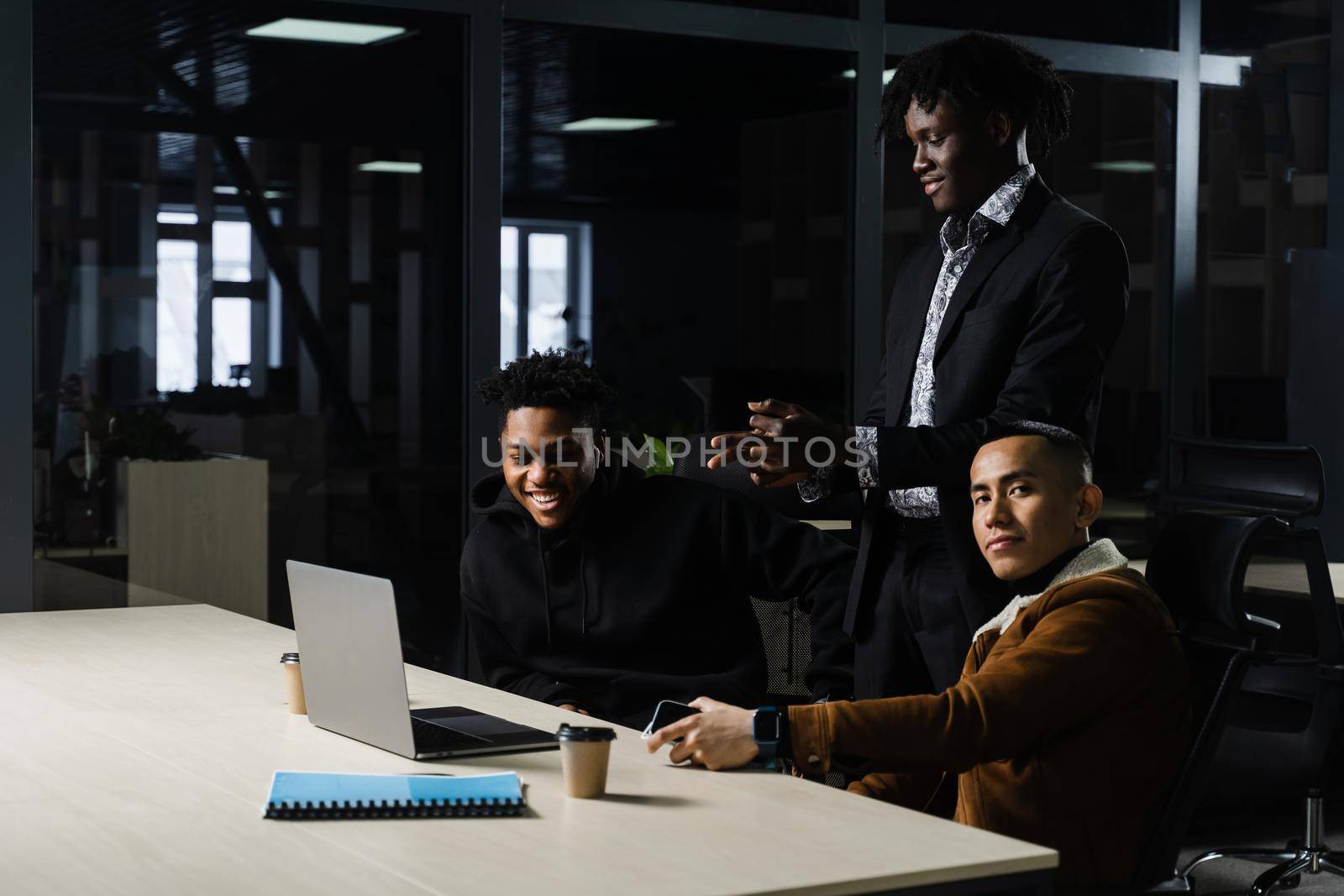 Multinational brainstorm group of colleagues working online on project in briefing room. Black african business man and asian work in team together. by Rabizo