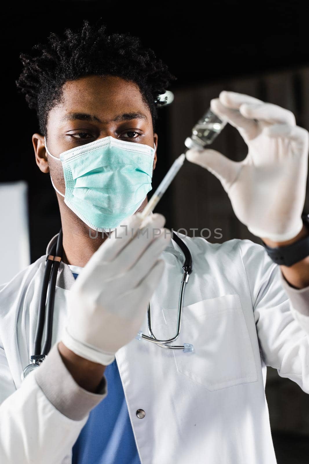 African doctor in a medical mask prepares to inject coronavirus covid-19 vaccine. Black doctor in white medical robe with syringe for making vaccination