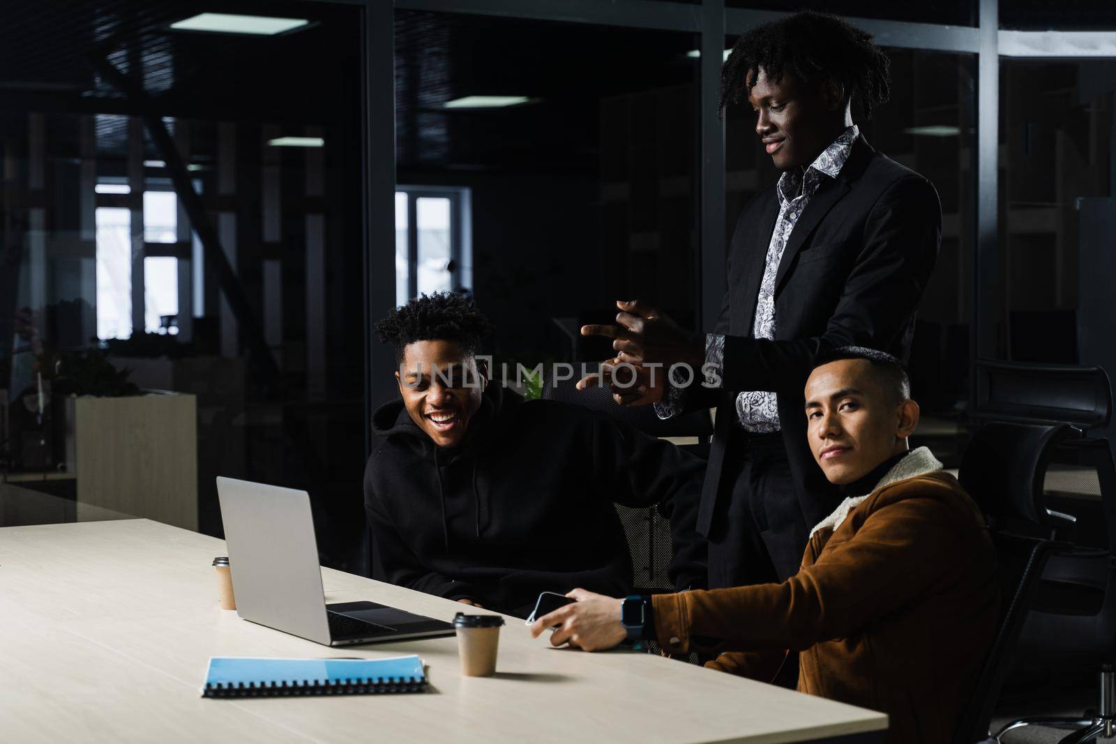 Multinational brainstorm group of colleagues working online on project in briefing room. Black african business man and asian work in team together. by Rabizo