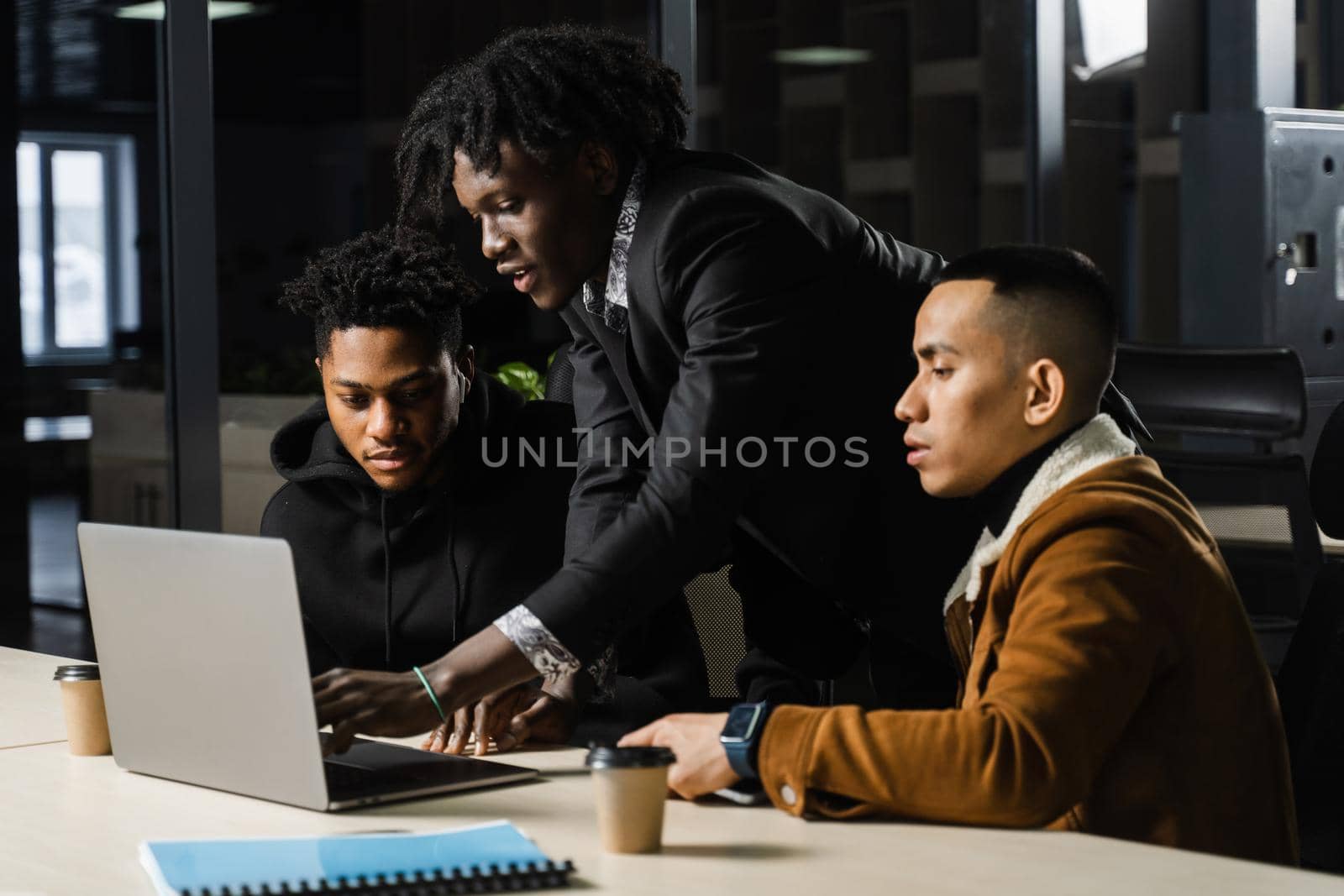 Mixed race of men teamwork on laptop in office. Discussing and working on on online projects