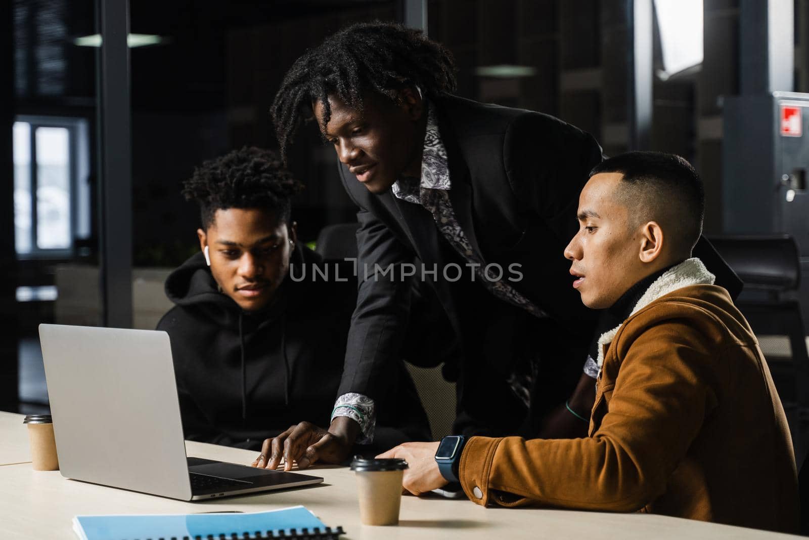 Mixed race of men teamwork on laptop in office. Discussing and working on on online projects. by Rabizo