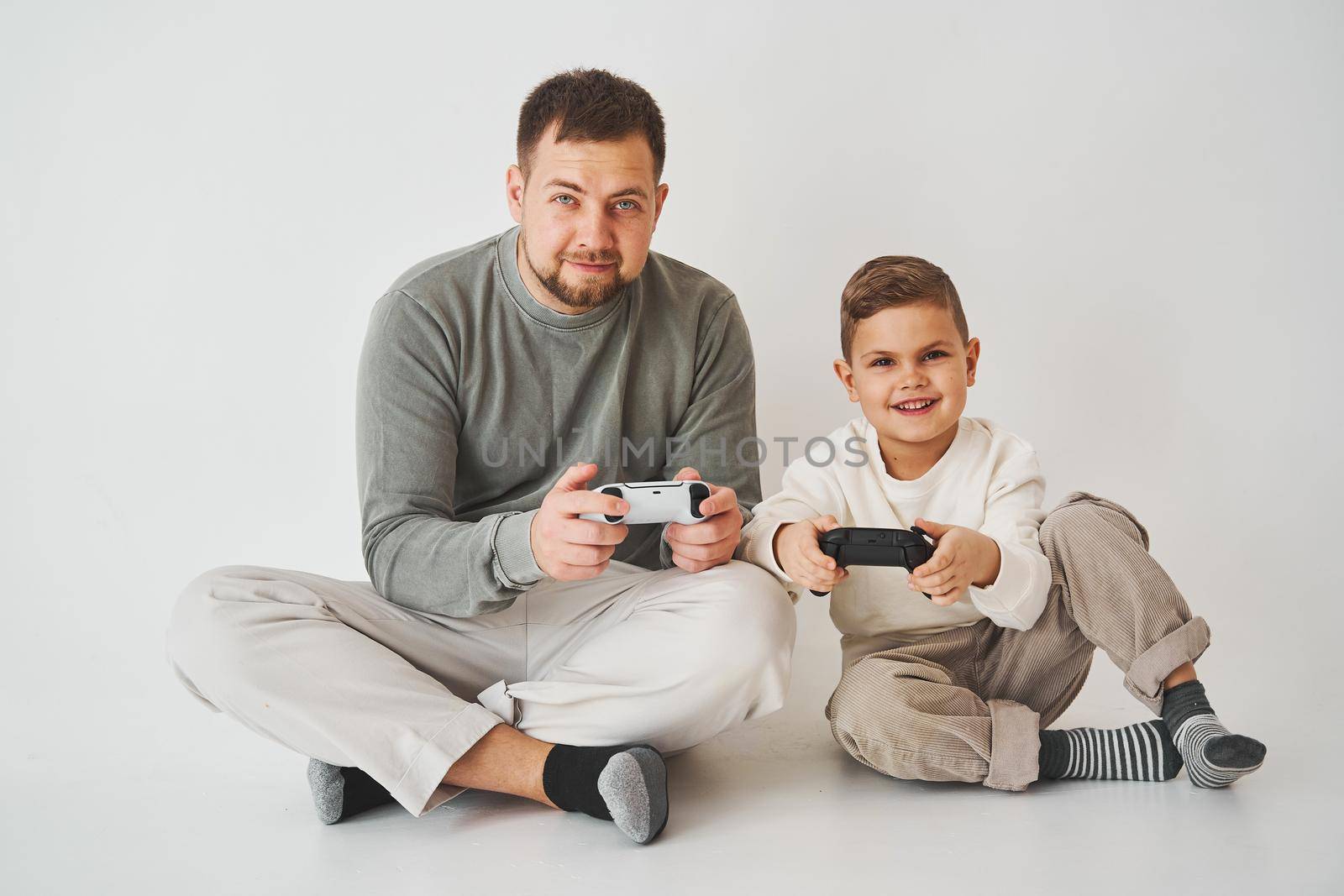 Emotional family playing console games on a white background. Father and son play gamepad games together