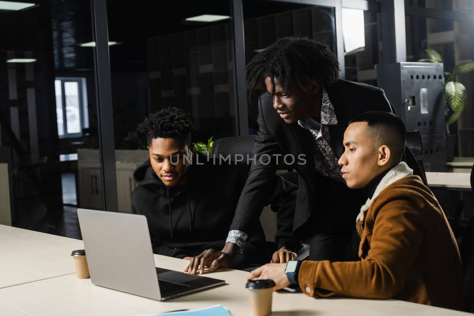 Multiethnic group teamwork of black african and asian employee working on laptop together. Discuss business process in team in office