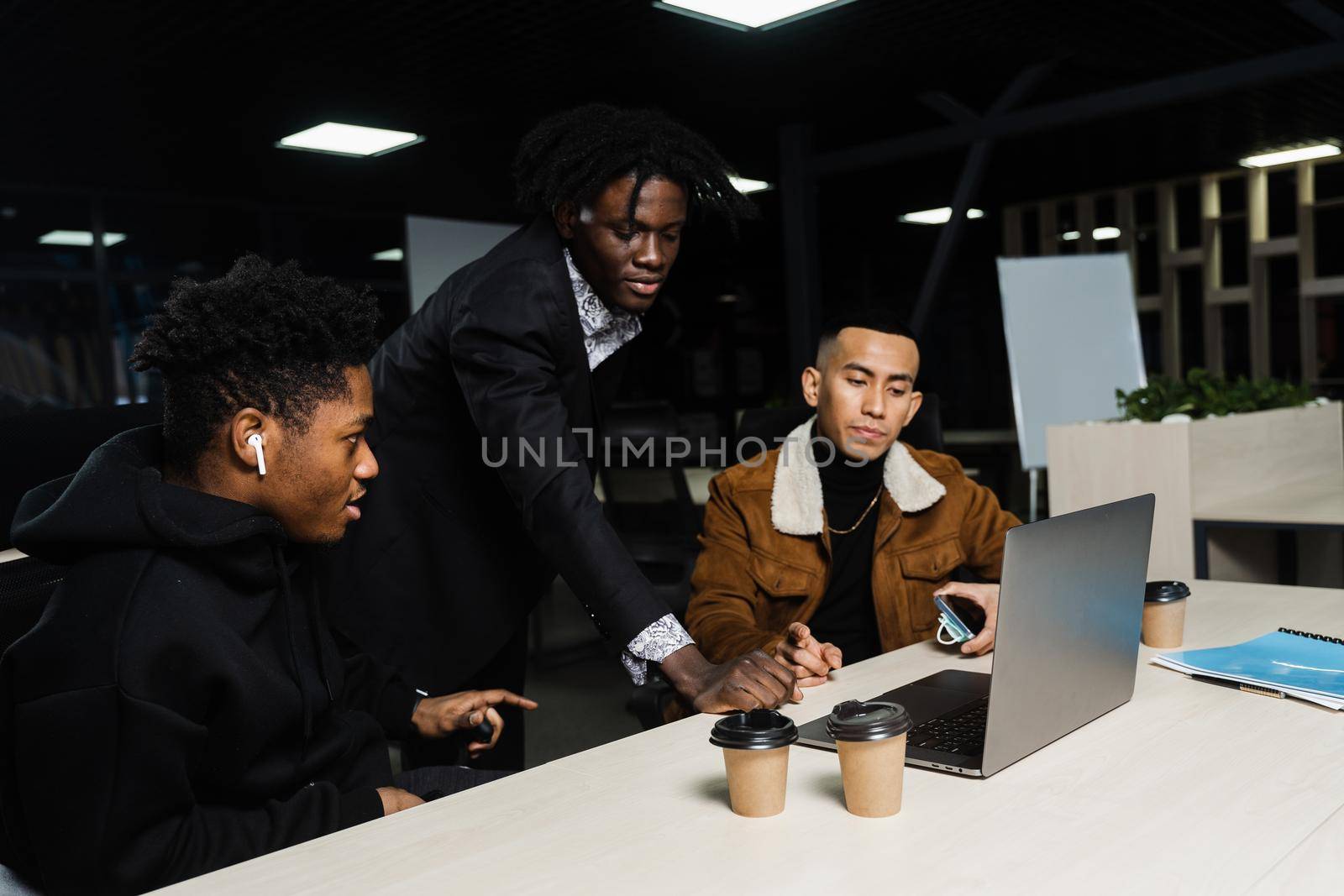 Teamwork of 2 black african and asian with laptop. Colleagues in informal clothes working on business project in the office. by Rabizo