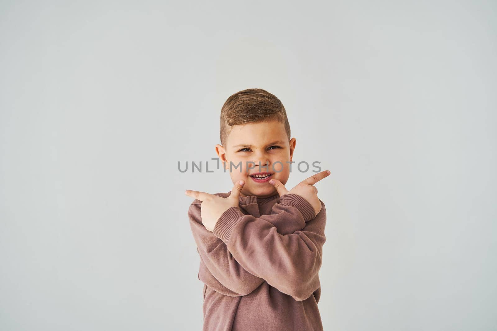 Happy handsome child boy smiling and points his fingers up for choose. Business advertising for children stores and shops. by Rabizo