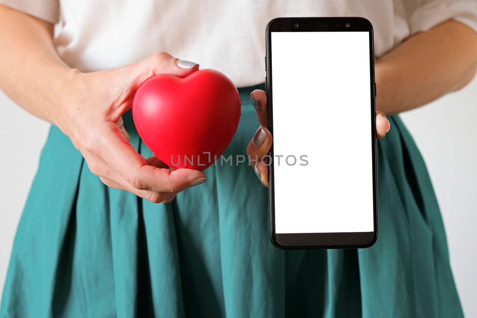 A woman's hands holding a heart symbol on belly and smartphone. Application for woman's health