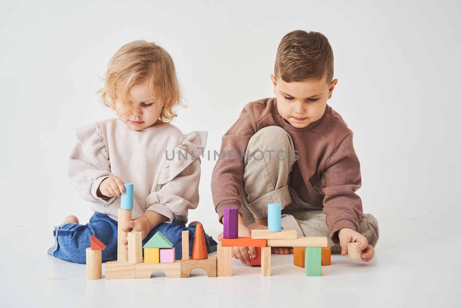 Boy and baby girl smiling, having fun and playing colored bricks toy on white background. Children have smiling and have fun together