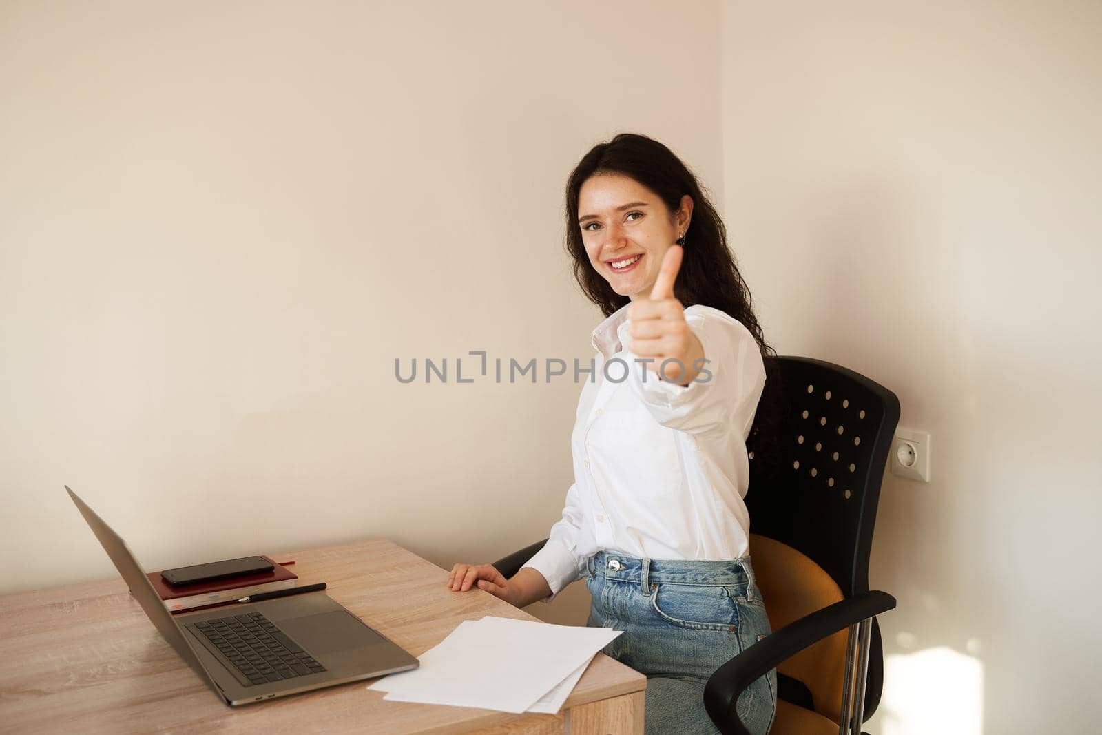 Girl showing thumbs up and smiling. Student studying online using laptop at home. Online education and distance learning