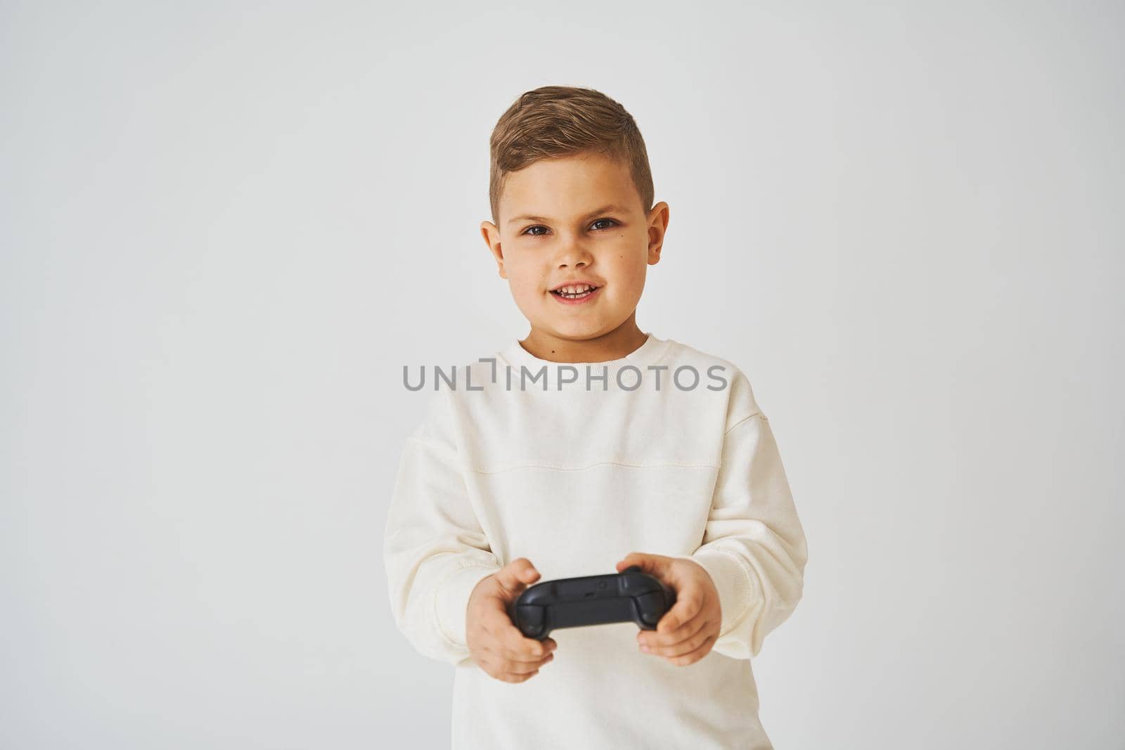 Happy child with gamepad on white background. Boy is playing games. by Rabizo