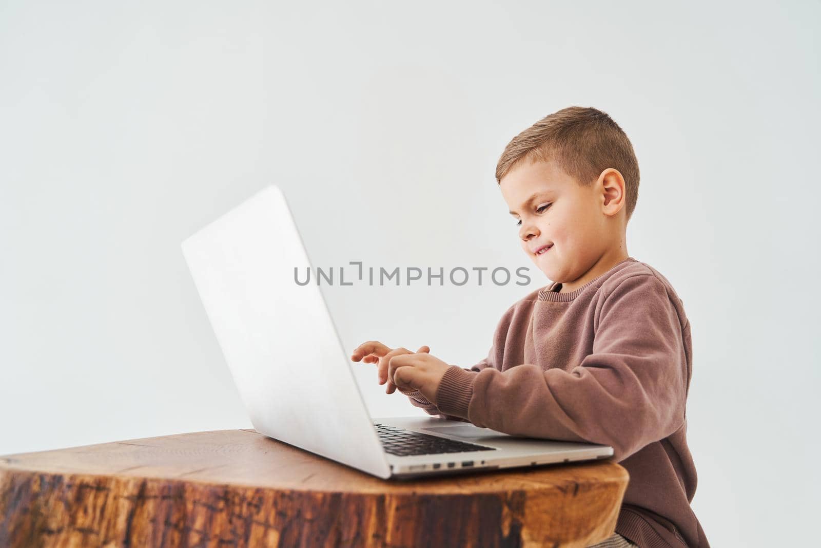 Emotional child with laptop talking with friends online. Handsome kid typing text on laptop and smile