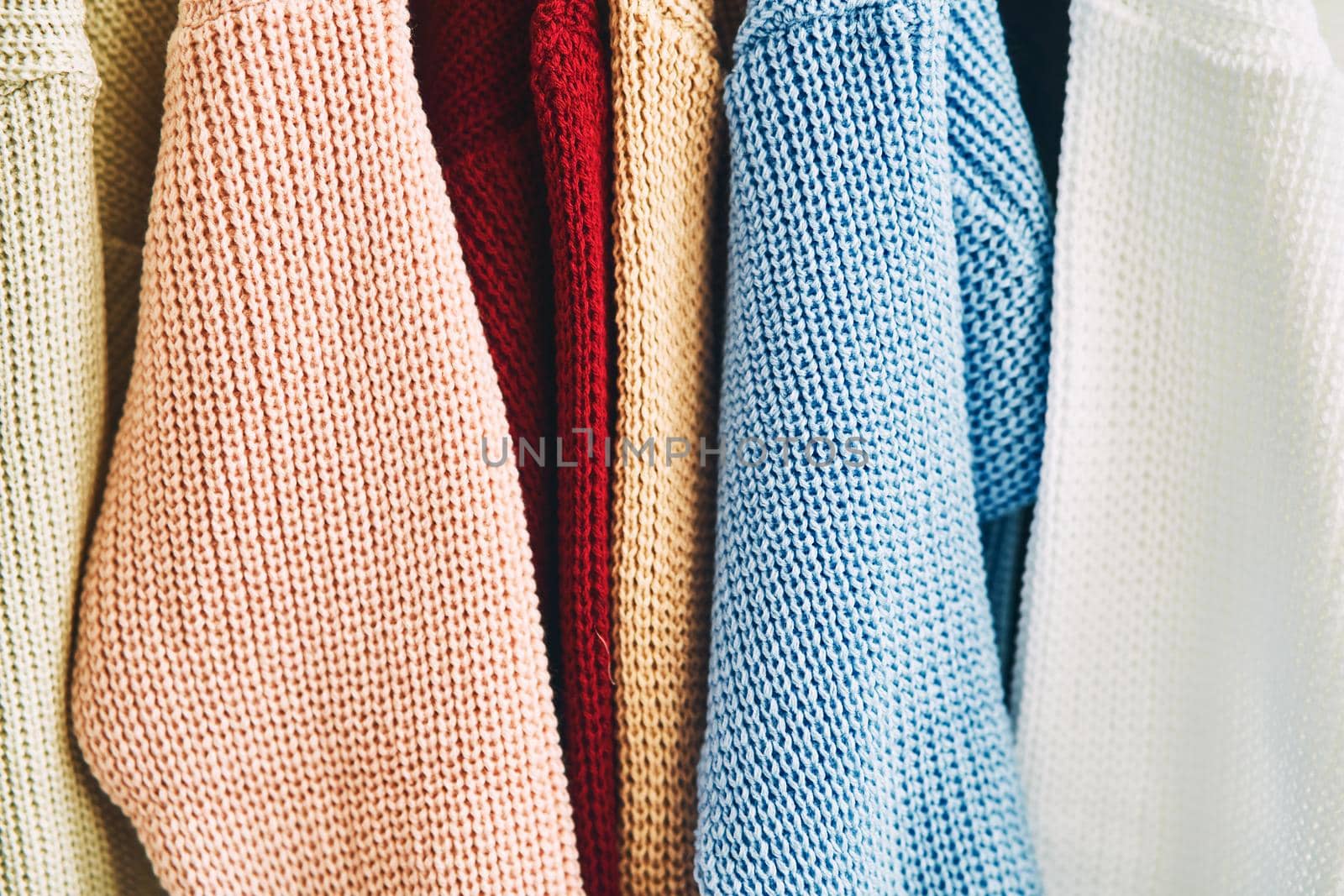 multicolored women's woolen sweaters on hangers. Sale in a fashion store. High quality photo