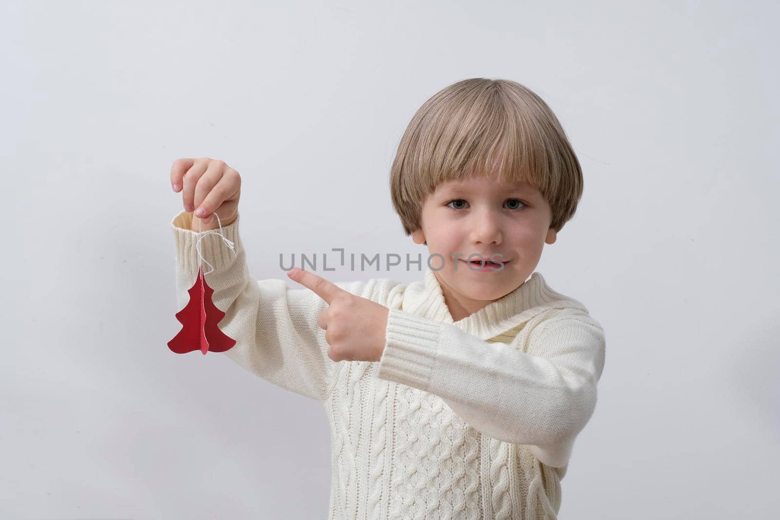 Child holding Christmas decoration in hand. Boy on white background. New year and x-mas concept. by natus111