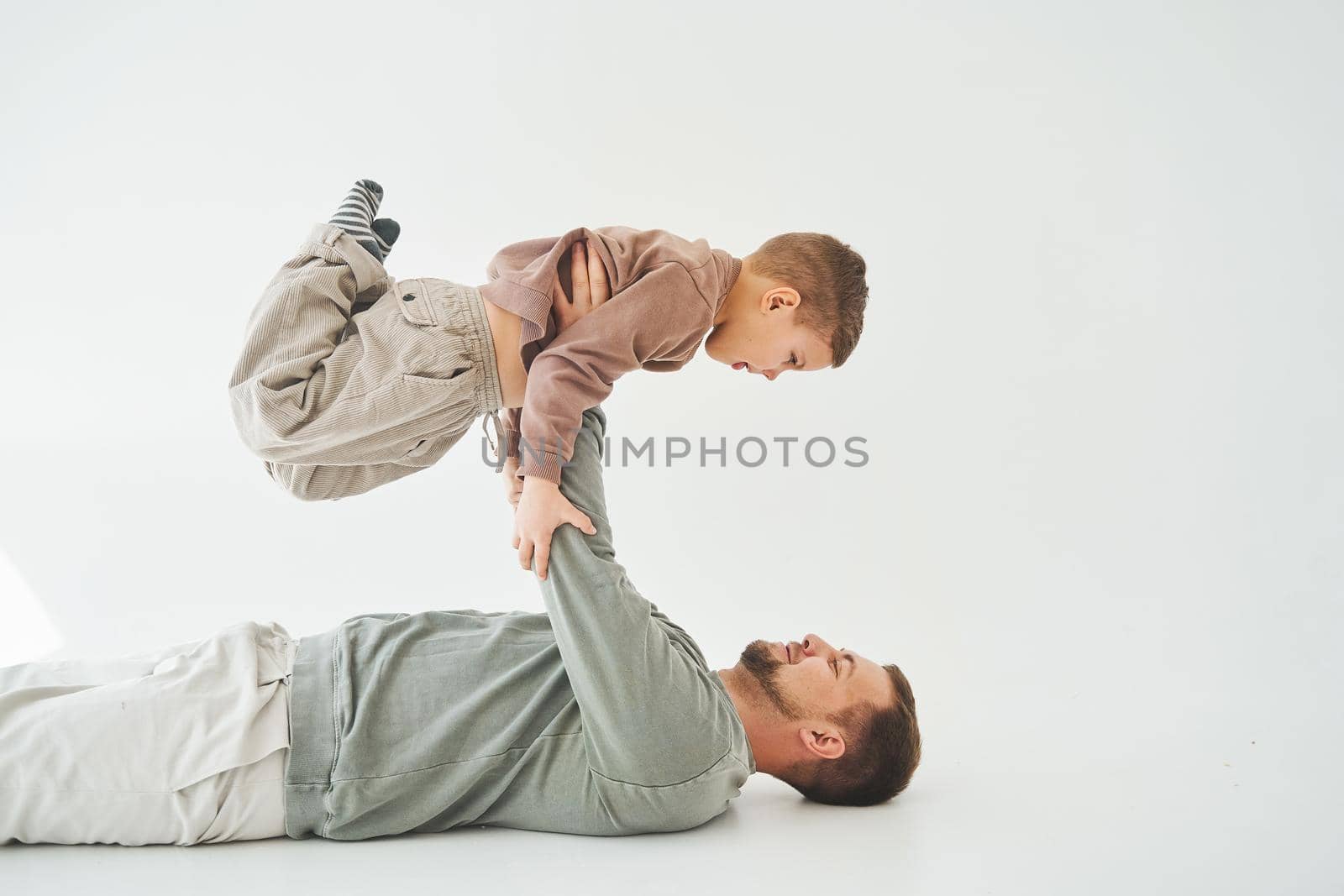 Paternity lifestyle. Father lifting child on white background. Dad and child smile and having fun together