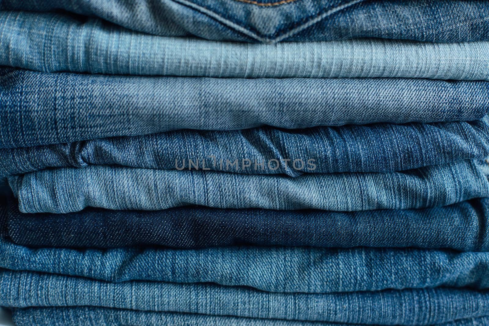 Stack of a stack of old jeans various shades of blue jeans. Denim jeans texture. Denim background texture for design. Canvas denim texture. Blue denim background.