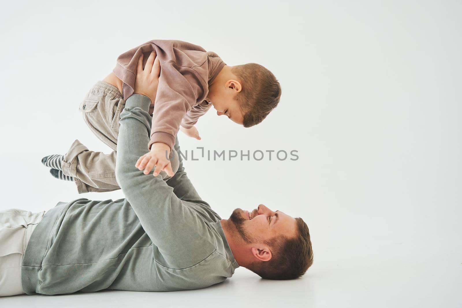 Father raises his son and plays with him, have fun and spend time together. Paternity. Handsome son in his fathers arms