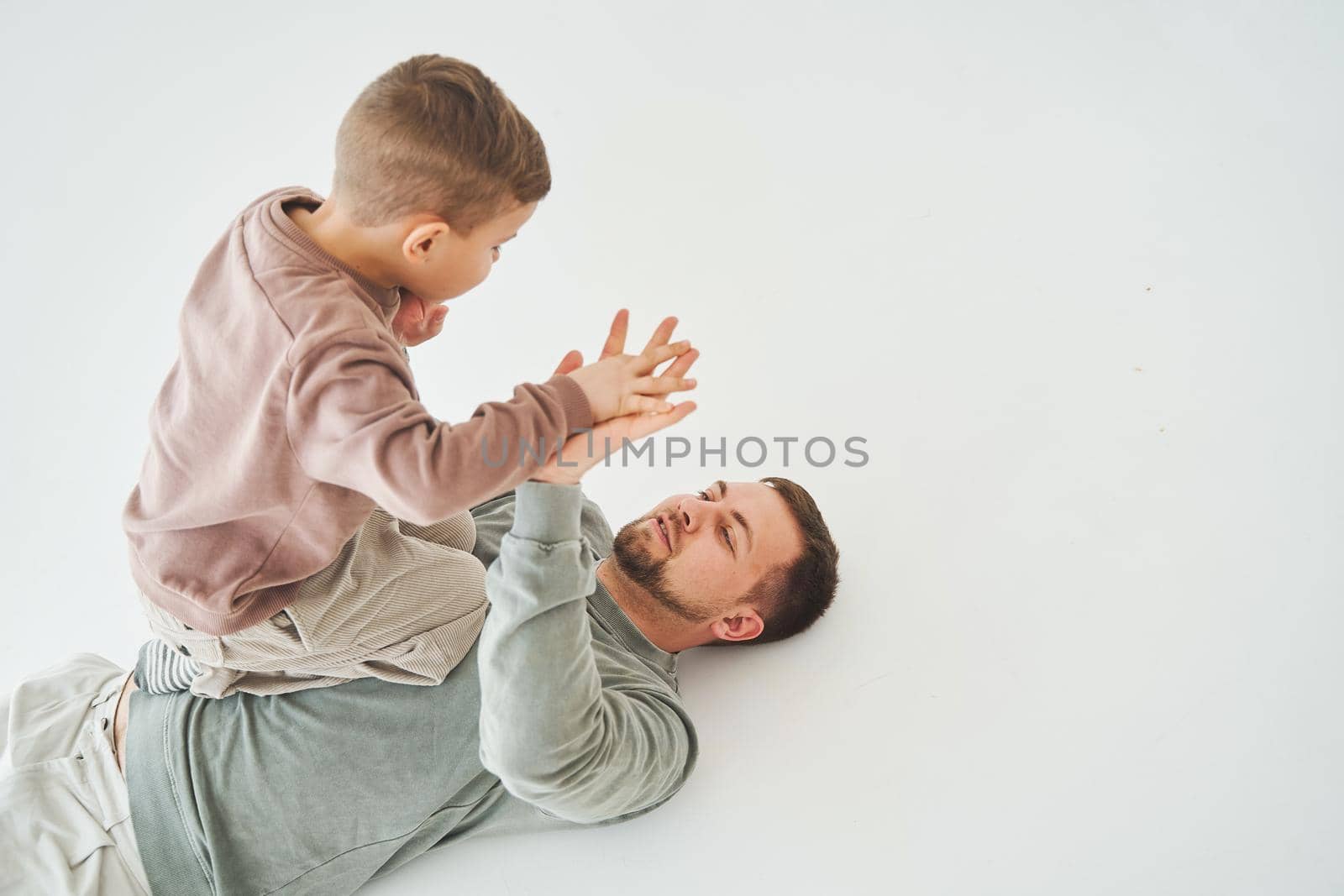 Father and son have fun and fool around together on white background. Child laughs with dad. Fatherhood. Child care