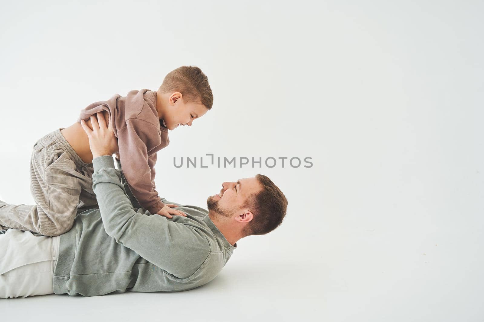 Father raises his son and plays with him, have fun and spend time together. Paternity. Handsome son in his fathers arms