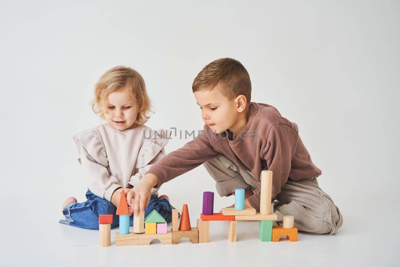 Boy and baby girl smiling, having fun and playing colored bricks toy on white background. Children have smiling and have fun together. by Rabizo