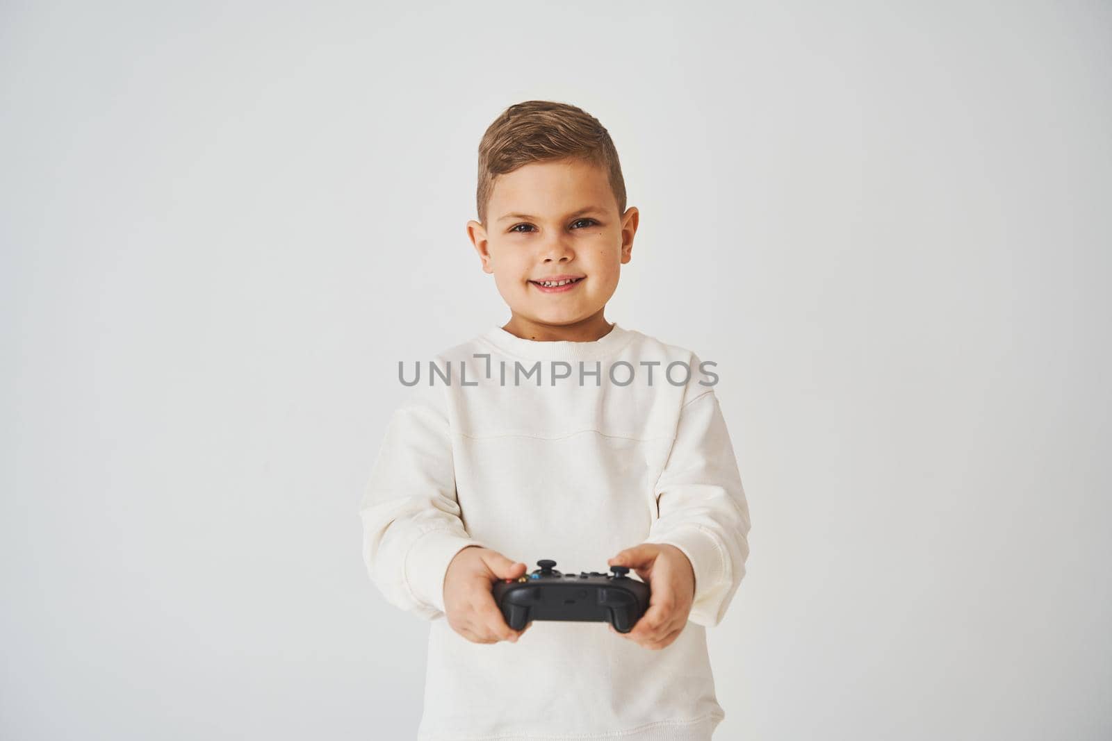 Emotional child with gamepad on white background. Boy is playing games