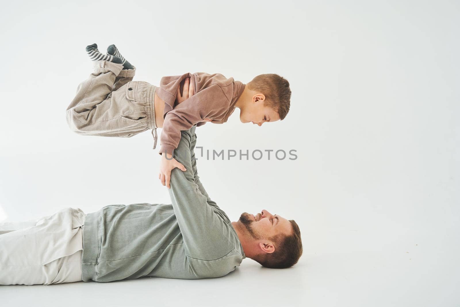 Paternity lifestyle. Father lifting child on white background. Dad and child smile and having fun together. by Rabizo