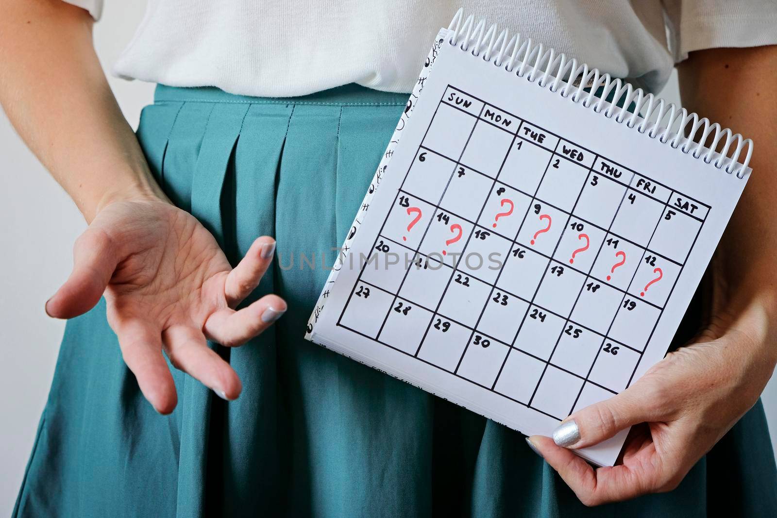 Woman holding calender with marked missed period. Unwanted pregnancy, woman's health and delay in menstruation causes.