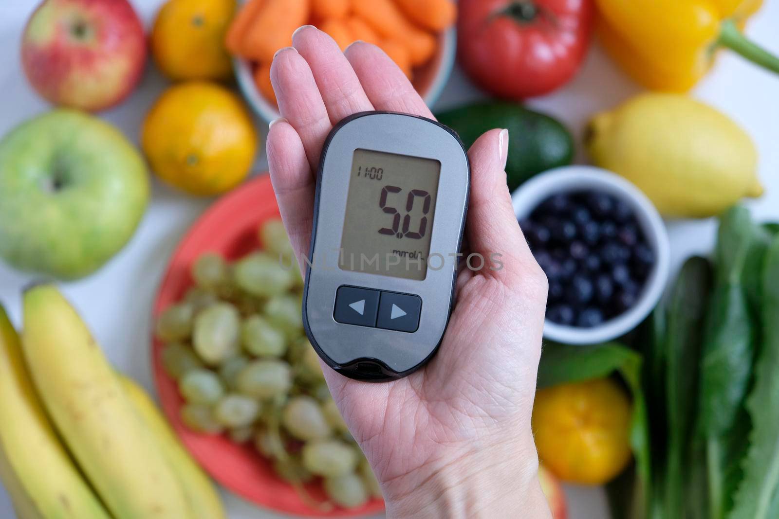 Diabetes concept: glucometer in hand and healthy food. Nutrition cause diabetic desease by natus111