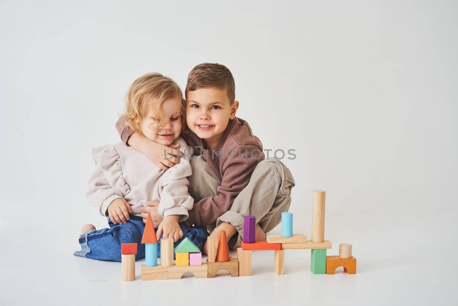 Boy and girl smiling, having fun and playing colored bricks toy on white background. Children have smiling and have fun together