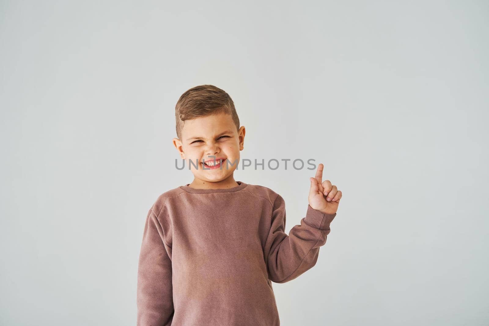 Happy handsome child boy smiling and pointing finger right side. Business advertising for children stores and shops. by Rabizo