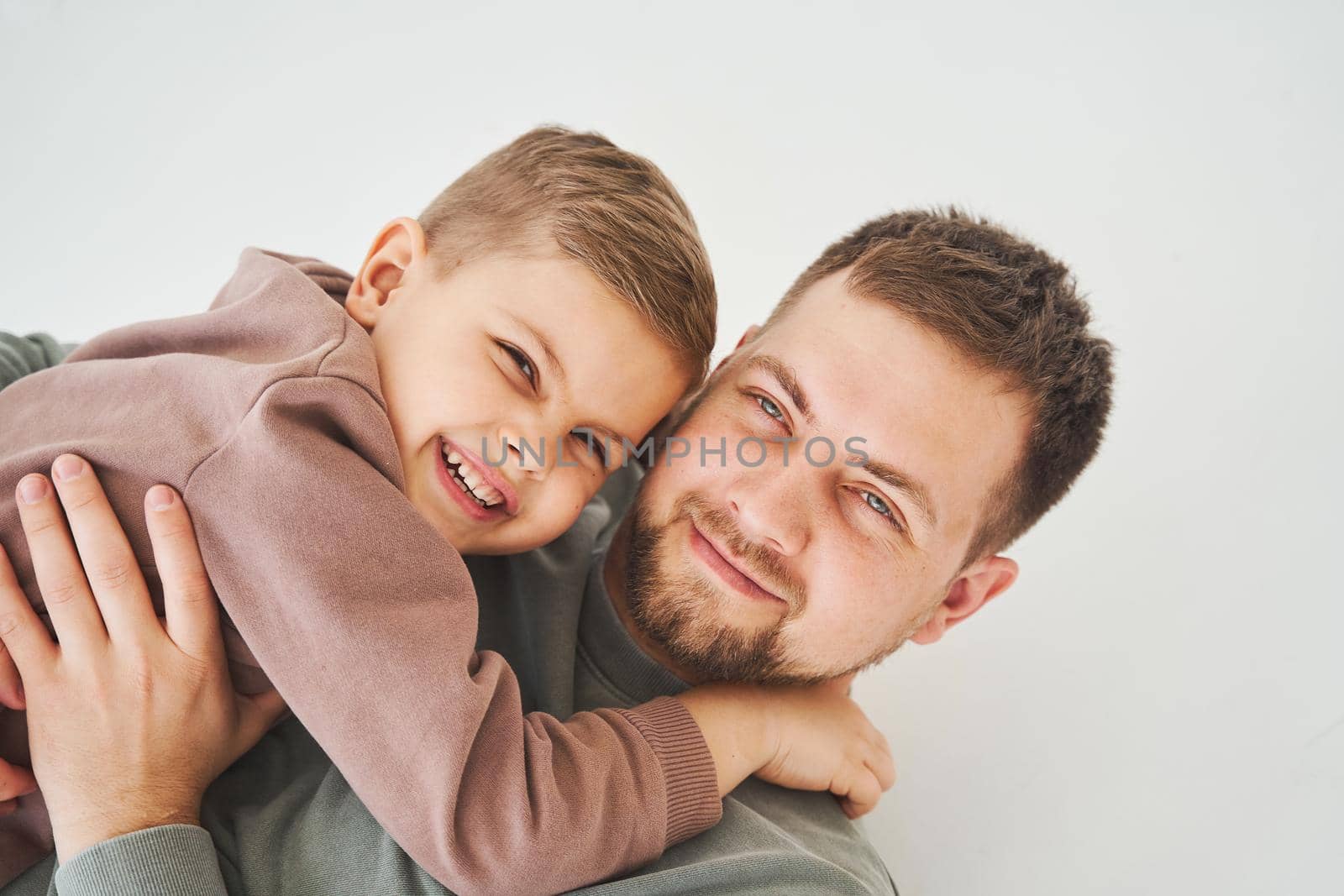 Close-up portrait of smiling father and son. Handsome dad and cheerful and emotional kid. Paternity