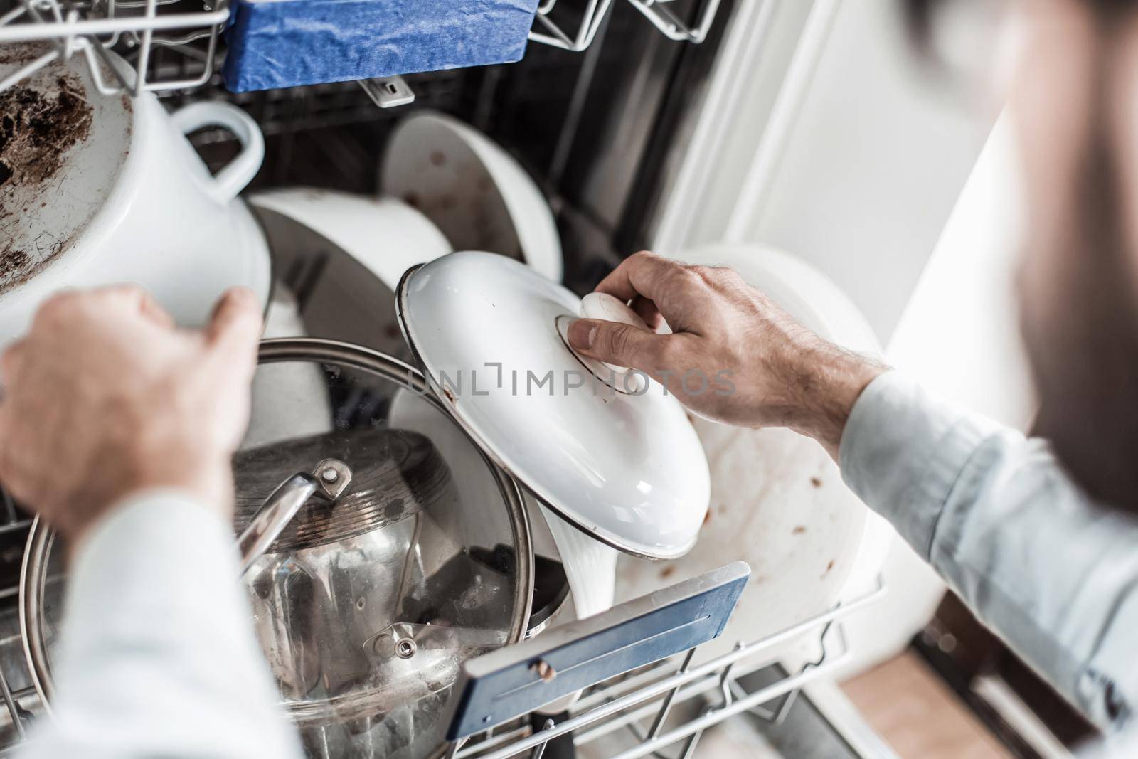 young man pulls the dishes out of the dishwasher by asdf