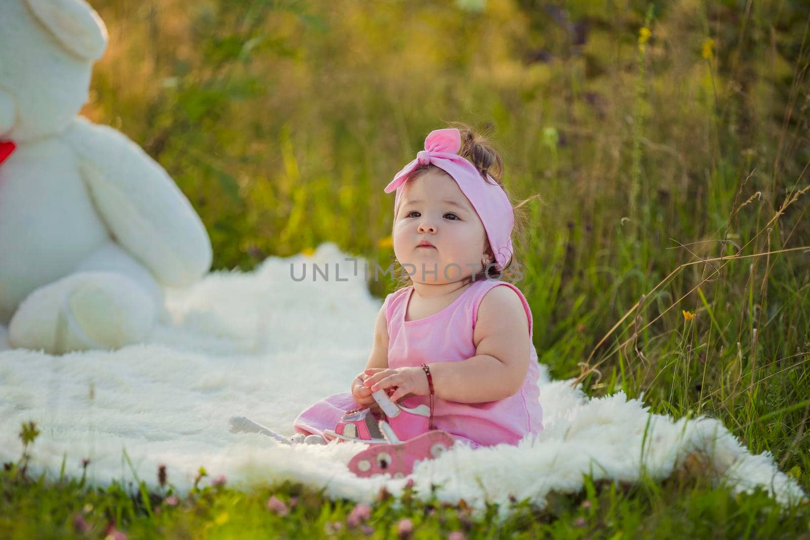 girl in a pink dress sitting on a blanket