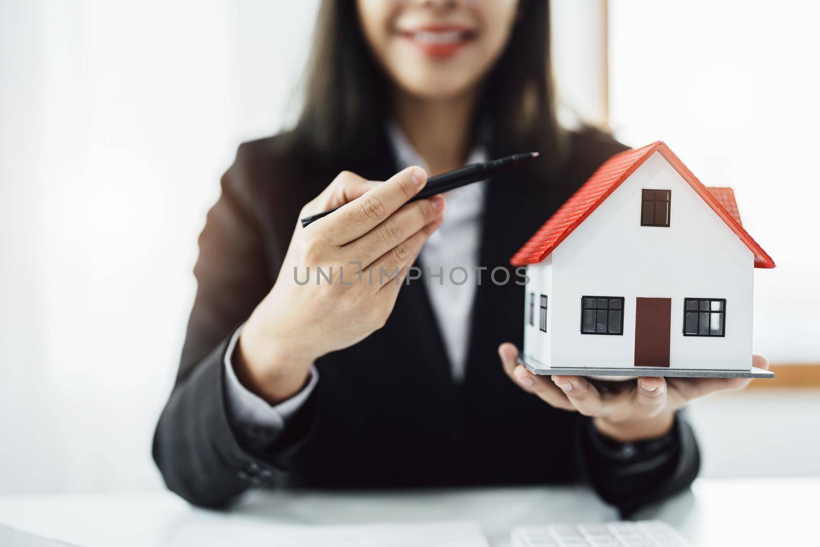 Law, agreement, contract, mortgage, woman holding a pen, pointing at a house to see the interest rate and asking for the limit to assess the risk before buying a house by Manastrong