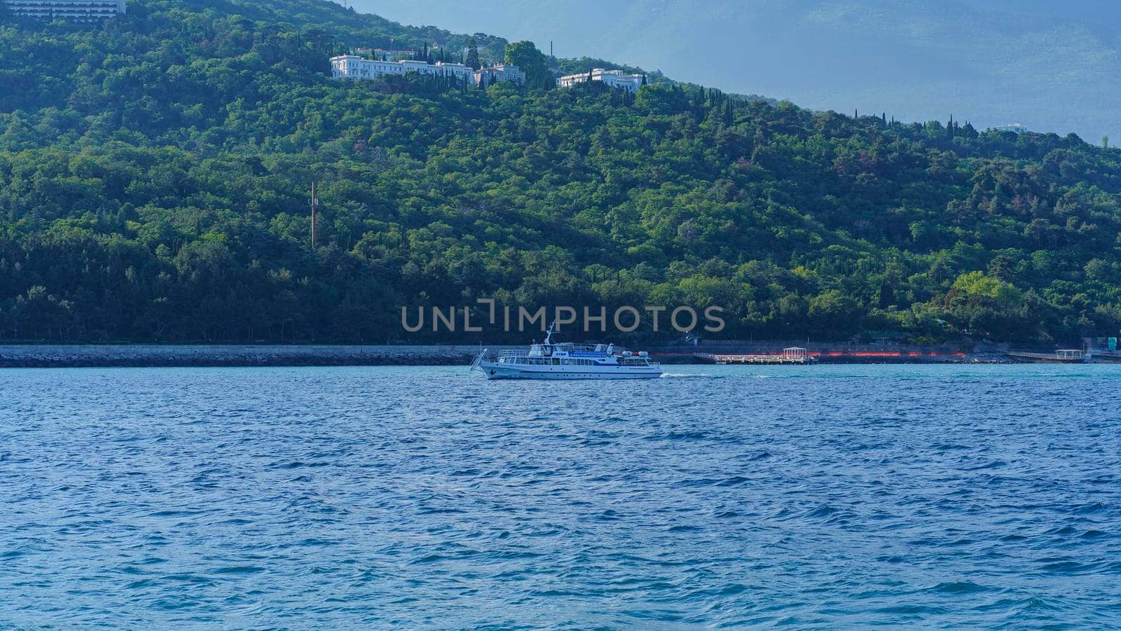 Yalta, Crimea-June 12, 2021: Seascape with a pleasure boat against the backdrop of the coastline.