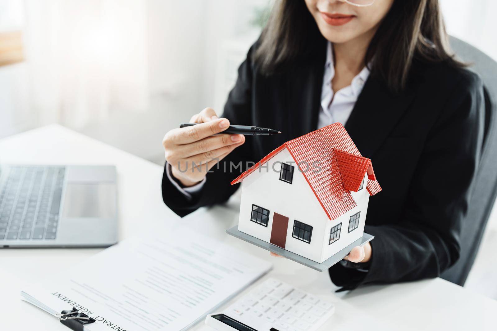 Law, agreement, contract, mortgage, woman holding a pen, pointing at a house to see the interest rate and asking for the limit to assess the risk before buying a house.