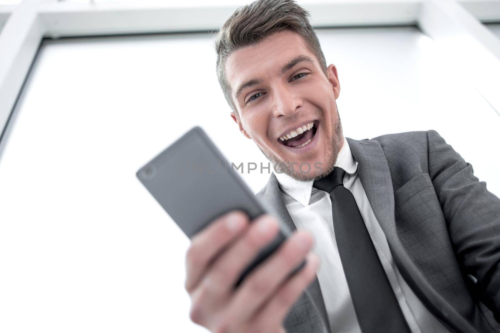 a young businessman read a good news in the phone. he will look into the camera.